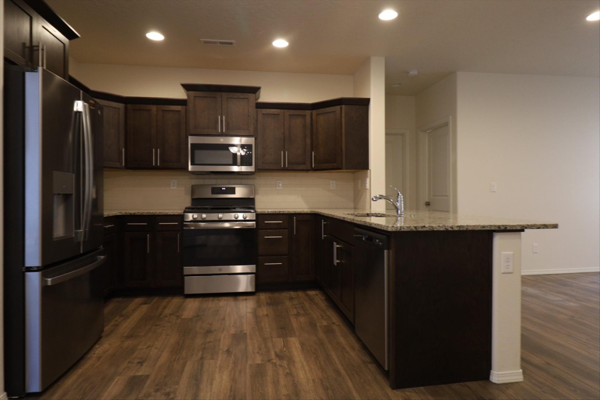 Kitchen with dark wood cabinets, granite counters, stainless gas range and full appliance package