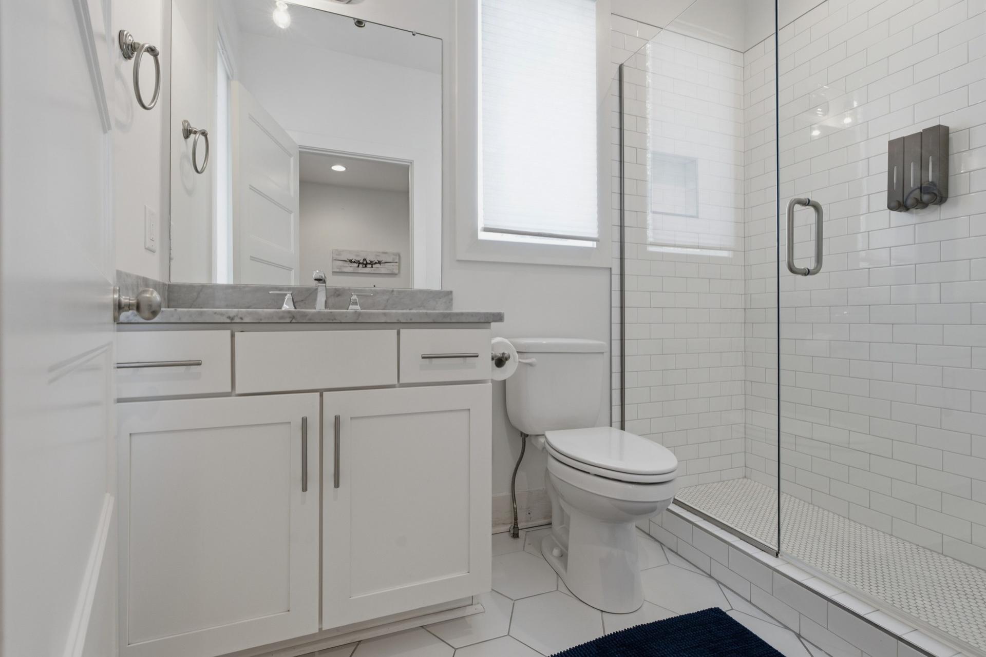 Full bathroom with marble-look vanity and glass shower