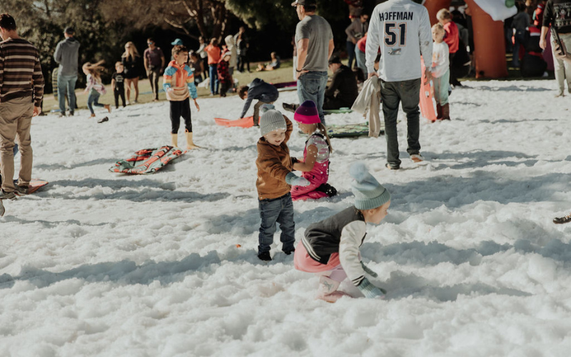 Families playing in real snow at Cane Real Estate Snow Day 2025, Kate Sessions Park