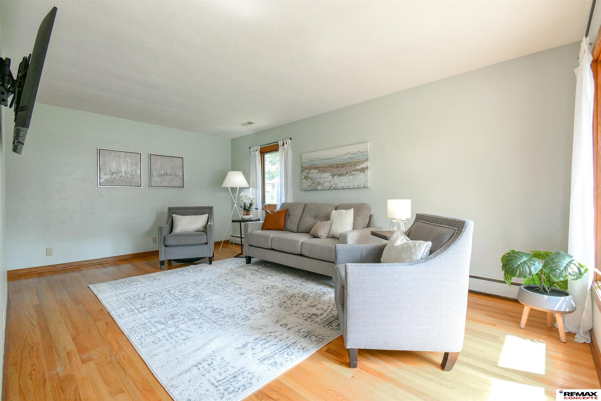 Hardwood-floor living room after staging with real furniture, rug, artwork and plants